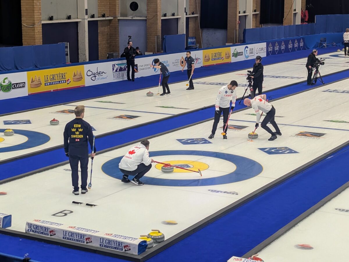 Canada's Ryan Harnden sweeps a curling stone delivered by Geoff Walker, not pictured, while Colton Lott walks alongside during the sixth end of a game against Sweden at the 2026 World Men's Curling Championship in Ogden, Utah, on Tuesday, March 31, 2026. (Ryan Olson, Standard-Examiner)